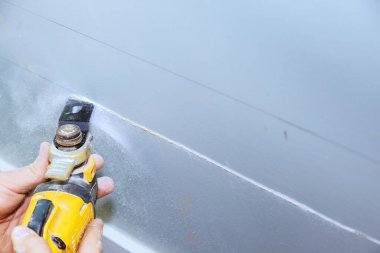 Duvardan elektrik kablosu geçirmek için alçı tahtayı kesmek için çoklu araç kullanmak