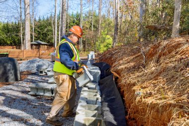 Yeni inşaat işçisi geliştirme sürecinde beton bloklar kullanarak istinat duvarı inşa ediyor