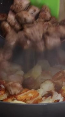 Roasted potatoes and meat cooked in frying pan with vegetable oil with of traditional cooking technique.