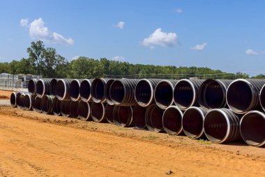 İnşaat alanında kanalizasyon tesisatı için endüstriyel boyutta siyah plastik borular var..