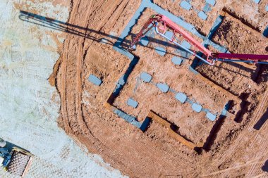 İnşaatçı evin temellerine ıslak beton dökmek için beton pompa kullanıyor..