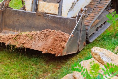 Mini buldozer dünya ile verimli bir şekilde çalışıyor, çeşitli peyzaj işleri yürütüyor bölgenin genel görünümünü geliştiriyor..