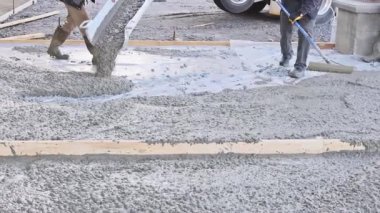 İnşaat şantiyesinde çalışan işçiler beton çökmeye hazır mala ile garaj yolu için betonu dengeleyecekler