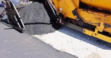 Yol yapım çalışmaları sırasında asfalt kaldırım makinesi ve buharlı yol silindiri, yeni yol katman süreci yerleştiriliyor