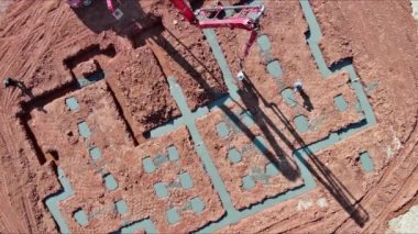 Beton pompa kullanılarak inşaatçı tarafından evin temellerine ıslak beton dökülüyor..