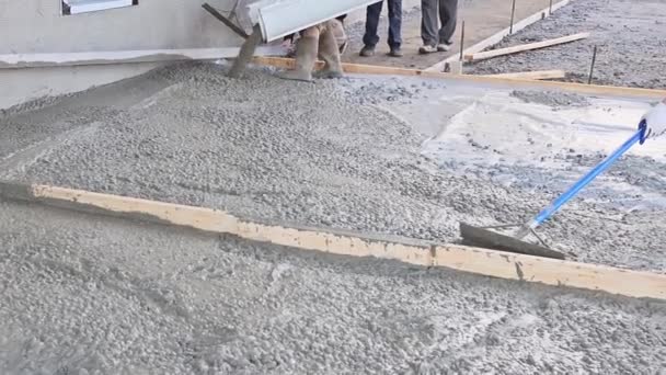 コンクリート労働者を注ぐ後 湿ったコンクリートセメント床を石膏するためにトロエルを使用しています — ストック動画