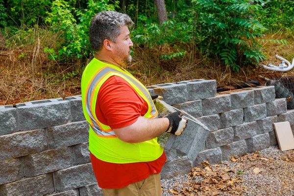 stock image Construction worker lifted concrete block positioned it on retaining wall.