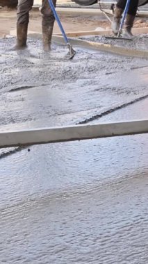İnşaat alanındaki işçiler durgun beton malayla garaj yolu için beton döşüyorlar.