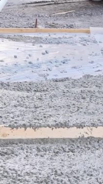 İnşaat şantiyesinde çalışan işçiler beton çökmeye hazır mala ile garaj yolu için betonu dengeleyecekler