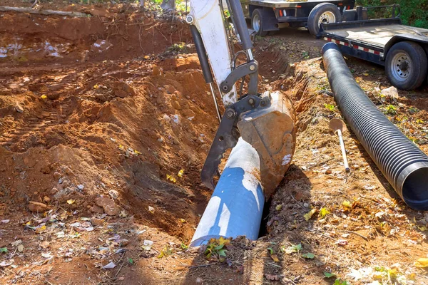 Ground work for underground worker uses tractor to installation concrete sewage pipes