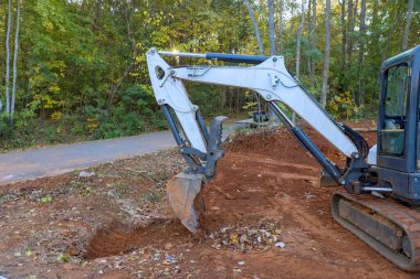 Kanalizasyon beton kanalizasyonunda çukur kazmak için traktör kullanmak bir boru projesi.