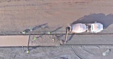 Yeni beton kaldırımlar inşa edilirken inşaat şirketinin çalışanları ıslak beton döküyorlar.