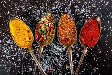 Masadaki çeşitli baharatlarla sıralanmış küçük kaşıklar.