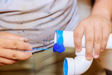 Tesisatçı yeni ev inşaatında drenaj için plastik PVC boruları yapıştırıyor