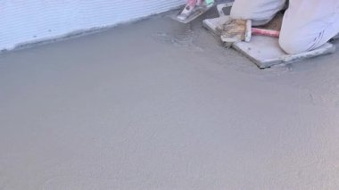 İnşaat alanındaki ıslak beton zeminde mala kullanan yetenekli bir beton işçisi.