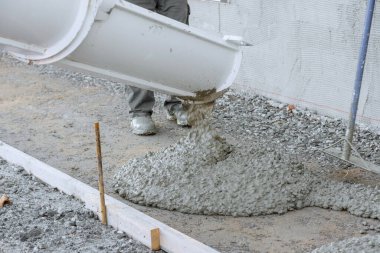 İşçiler yeni evler için beton karıştırma kamyonu kullanarak ıslak çimento döktü.
