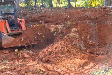 İnşaat alanındaki traktör, eklentileri dengelemek için ev yerleşim alanı için zemin hazırlıyor.