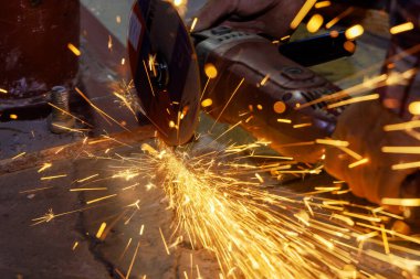 Demir işçisi metali kıvılcımla kesmek için aşındırıcı bir disk kullanırken,