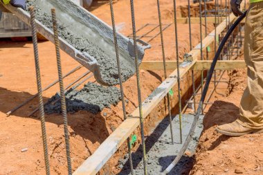 Evin temelini hazırlamak için siperlere beton döşeyen bir birey