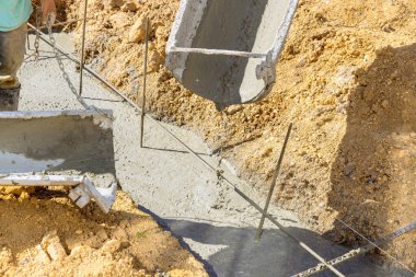 Evin temeli için siperlere beton döken bir kişi