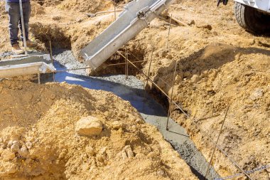 İnşaat işçilerinin ev temelleri için siperlere beton döşemesi