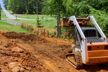 Mini buldozer dünya ile çalışıyor, toprağı hareket ettiriyor, peyzaj yapıyor, bölge iyileştirmesi yapıyor.