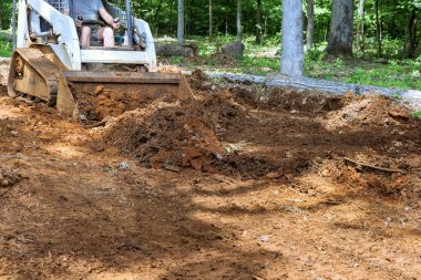 Toprakla çalışmak, hareket eden toprak, mini buldozerle bölgenin manzarasını iyileştirmek.
