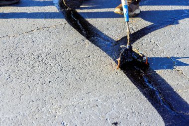 Çalışan yama sırasında asfalt çatlaklarını doldurarak zift emülsiyonu yol yüzey yenileme çalışmalarını gerçekleştirir