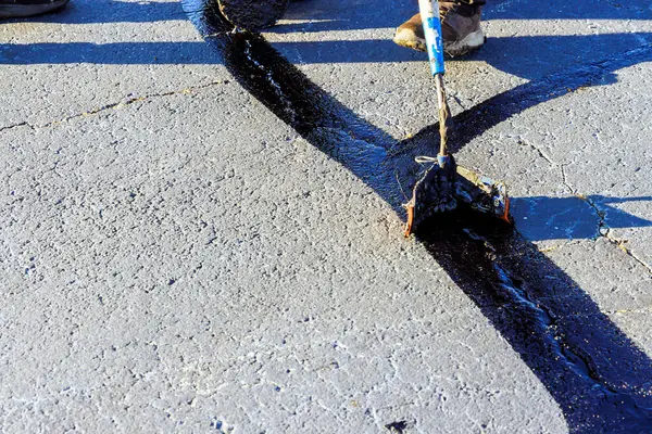 stock image During worker patcher performs coated filling asphalt cracks sealing bitumen emulsion road surface restoration work