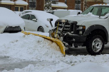 During heavy snowfall, snowplow truck removes snow from parking lot clipart