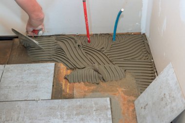 Döşeme fayanslarını döşemek için, beton üzerine mala yapıştırıcı..