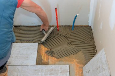 Döşeme döşemeleri için beton zemine yapıştırıcı sürüyorum..