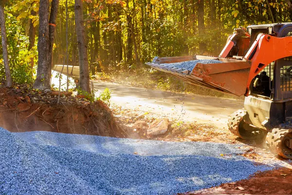 Stock image Preparation of base for new road consists laying crushed stone gravel filled up with by tractor