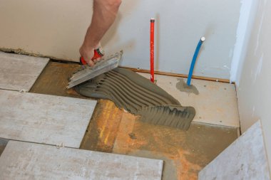 Beton zemine yapıştırıcı sürerek fayans döşeme hazırlığı.