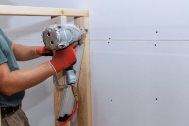 İnşaatçılar, ev destek iskeletine tahta kirişler çakmak için bir hava çekici kullanıyorlar.