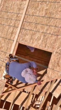 Marangoz inşaat işçileri gelecekteki evlerinin çatısında kontrplak çiviler çakıyor.