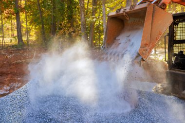 Traktör kullanarak, yeni yola zemin hazırlamak için ezilmiş taş çakıl döşeyeceğiz.
