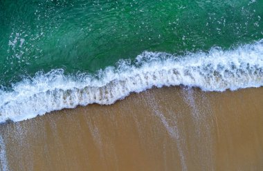 Havadan bakıldığında okyanus dalgalarının kumlu kıyılara çarptığını görüyoruz..
