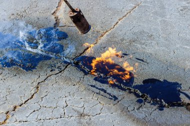 İşçi yaması asfalt yüzeylerini kaplama, çatlakları doldurma, mühürleme, zift emülsiyonu uygulayarak onarmak için çalışır