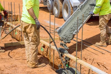 Beton vibratör kullanarak inşaat işçisi evin temeli için siperlere beton sıkıştırıyor