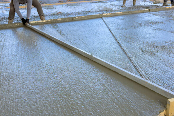 Бетон заливают для подъездной дорожки в новом доме с мокрым цементом