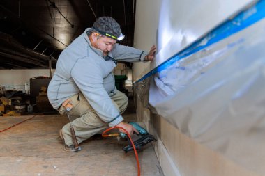 İnşaat şirketinin bir çalışanı işinin bir parçası olarak ahşap pervazları odaya çiviliyor.