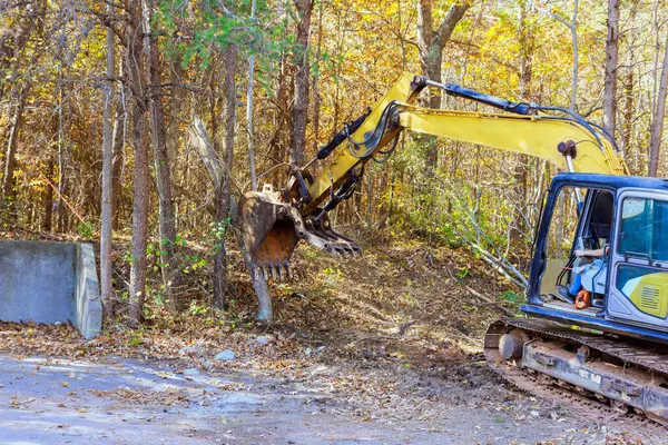 In order to prepare land for construction builder uproots trees at forest using tractor