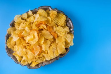 Mavi arka planda, üst tabakta patates cipsi görülebilir.
