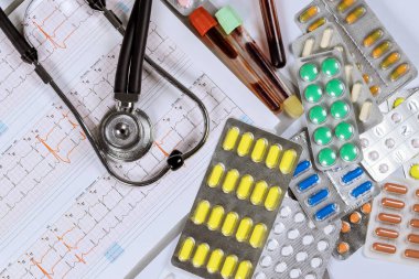 Doktor kalp hastalığının ve yüksek tansiyonun doğru tedavisi için su toplayan haplar kullanarak hastanın kardiyogramını kontrol ediyor.