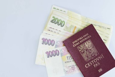 Çek Cumhuriyeti pasaportu, beyaz arka planda yığılmış çeşitli CZK koruna banknotlarıyla birlikte istiflenmiştir.