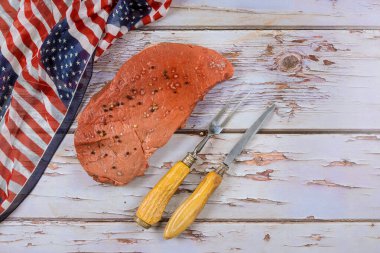 Amerikan bayramlarını kutlayan bir gelenek olarak çiğ biftek, Amerika Birleşik Devletleri bayraklarıyla süslenmiş masada hazırlanır.