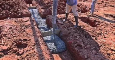 İnşaat alanında çalışan işçiler etrafa beton dökerek yeni ev temellerini oluşturuyorlar.
