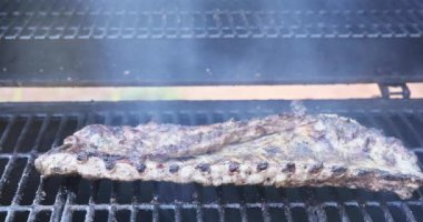 Barbekü ızgarasında, marine edilmiş domuz pirzolası kızartılıyor.