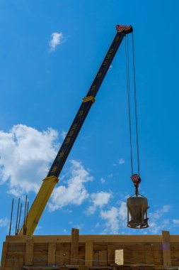 İnşaat sahasında, vinç resmi işlere dökmek için bir kova beton kaldırıyor.